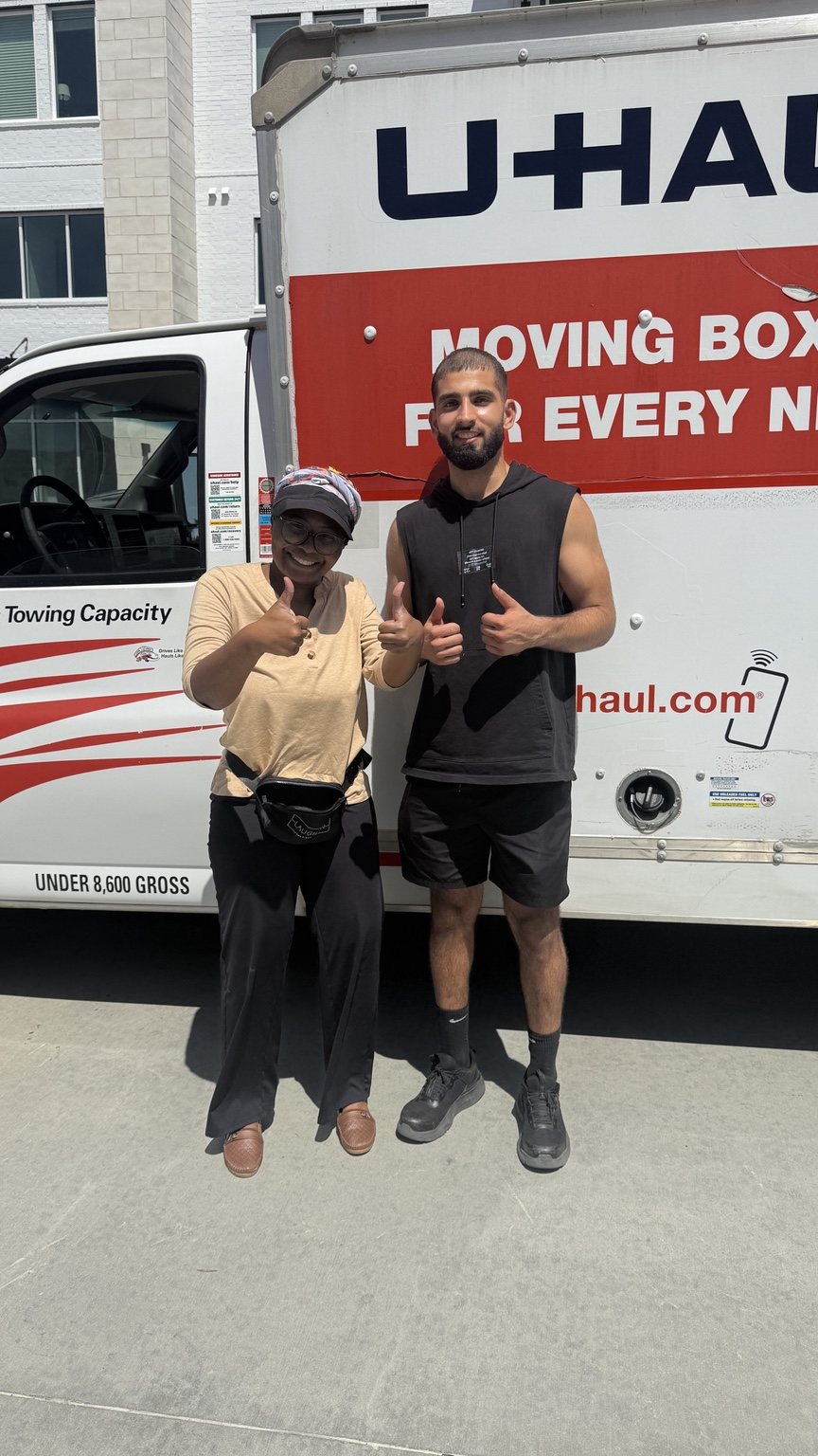 A Nahas Moving mover and a smiling customer giving thumbs up beside a U-Haul box truck